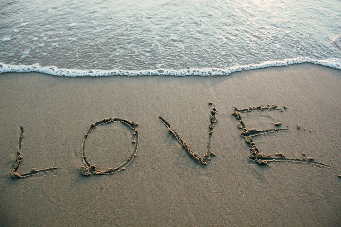 Love written in the sand near ocean waves, symbolizing emotions in an unpopular opinions poll setting.