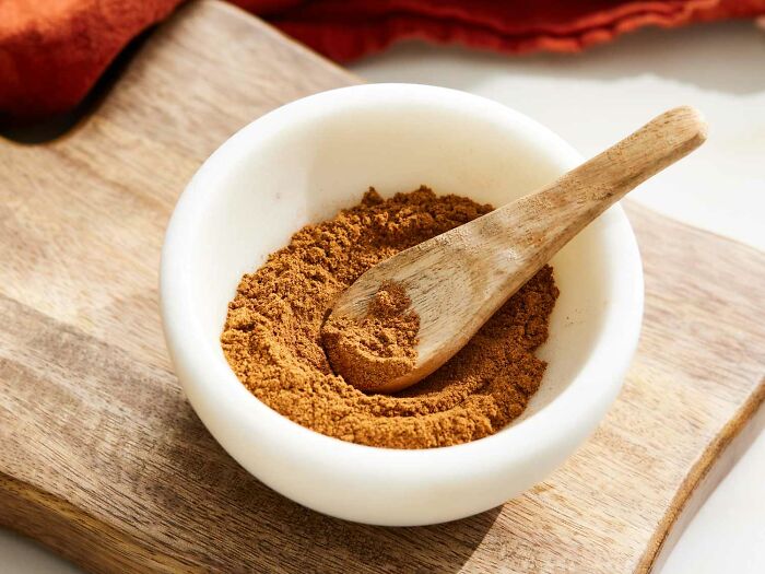 Close-up of ground spice in a white bowl with a wooden spoon, highlighting an unpopular opinions poll 4 theme.