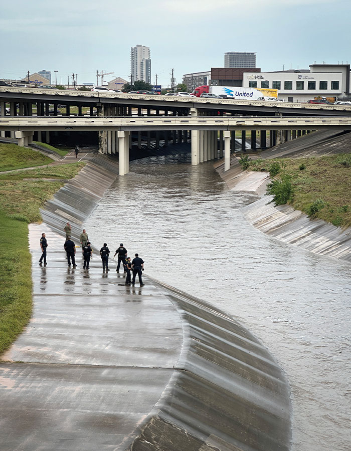 Police officers investigate near a Houston drainage canal amid fears of serial criminal activity after 16th body found.