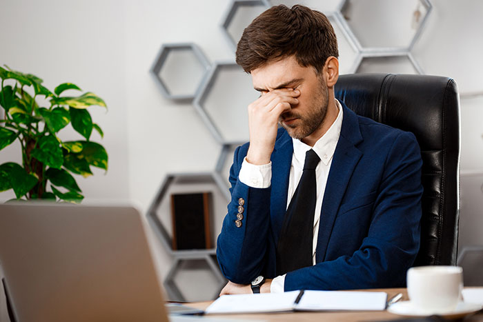 Man shuts down younger coworker flirt by looking stressed and rubbing his eyes while sitting at his office desk. Man shuts down younger coworker flirt by looking stressed and rubbing his eyes while sitting at his office desk.