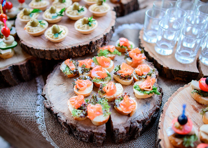 Assorted appetizers displayed on rustic wooden trays at a wedding reception without any cupcakes present.