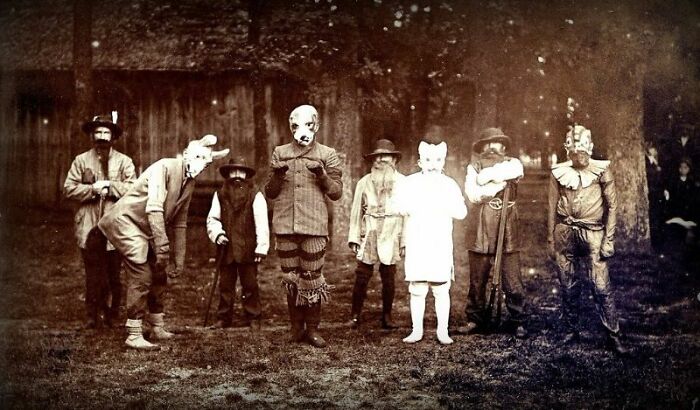 Group of people in vintage Halloween costumes from the past, showcasing terrifying and impressive outfit designs outdoors.