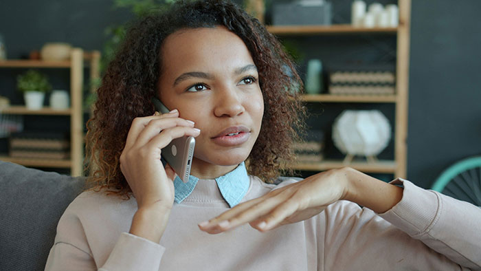 Young woman with curly hair talking on the phone, expressing frustration about mom abandoning kids and family struggles.