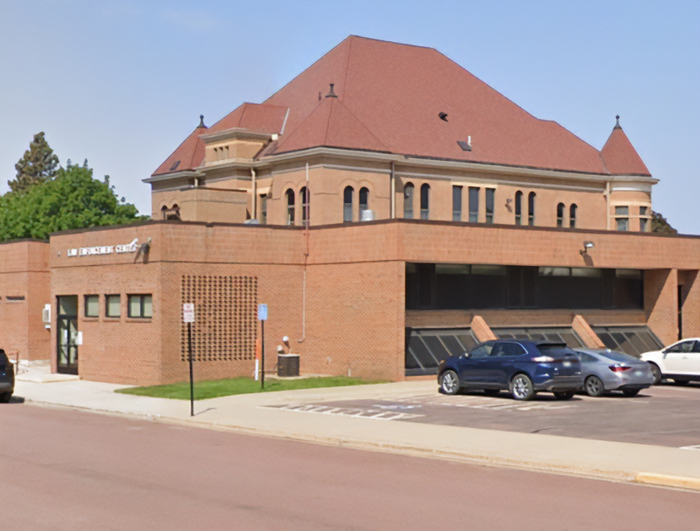Exterior view of a municipal building with parked cars outside, unrelated to woman gives her friend with benefits.