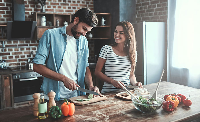 Couple cooking together in a modern kitchen, chopping vegetables and preparing a fresh salad with kitchen cheats.