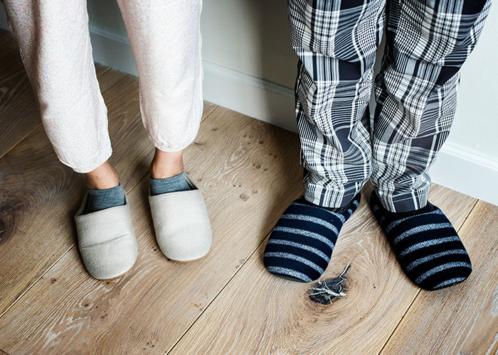 Pies de dos personas con pantuflas sobre suelo de madera en casa, coincidencia con palabras clave de autopsia y hallazgos médico forenses.