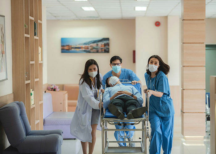 Medical professionals wearing masks transporting a patient on a stretcher during a medical examination in a hospital hallway.