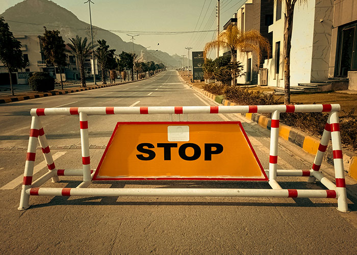 Roadblock with a stop sign on an empty street symbolizing halted investigations in medical examinations uncovering death truths.