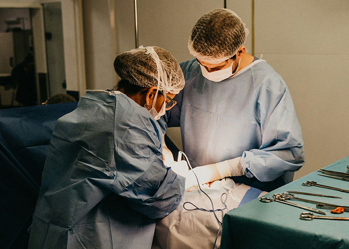 Two medical professionals in surgical attire performing a medical examination uncovering disturbing truths.