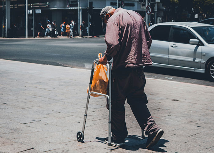 Hombre mayor caminando con andador en la calle, ilustrando hallazgos sorprendentes de autopsias médicas reales.