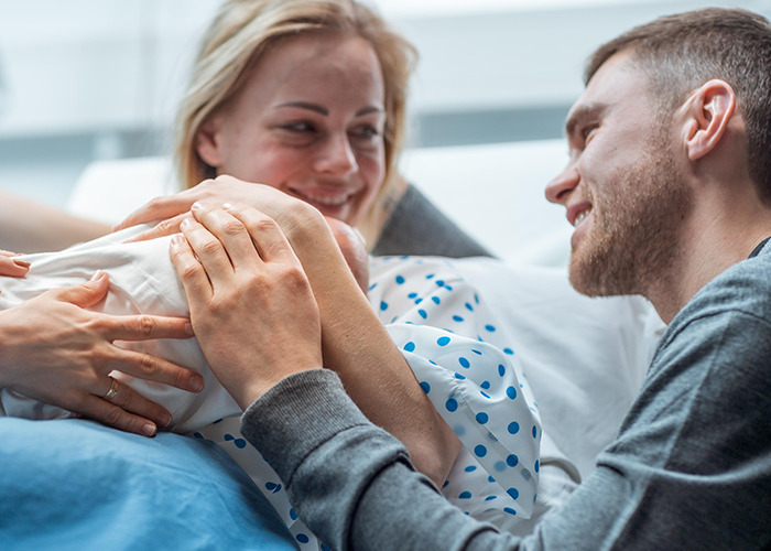 New parents in a maternity ward sharing a tender moment with their newborn, highlighting dad in maternity wards stories.
