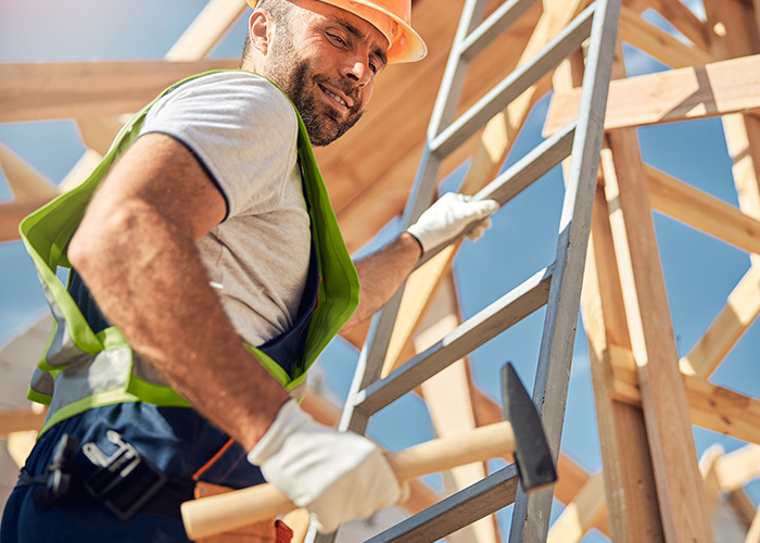 Construction worker in safety gear holding a hammer on a wooden frame, illustrating a dad in maternity wards story.