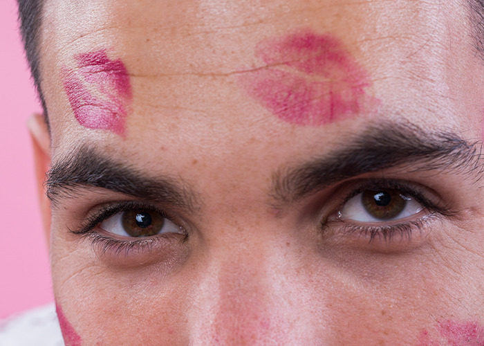 Close-up of a man's face with lipstick marks on his forehead and cheeks, highlighting dad in maternity wards moments.