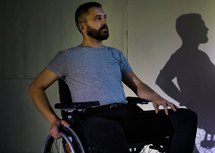 Man in wheelchair with confident posture casting bold shadow, illustrating powerful instant karma manifestations shared by people.