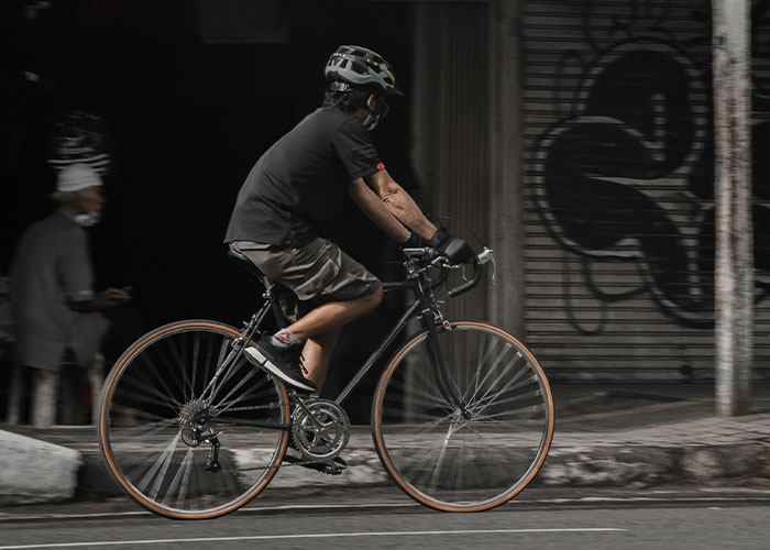 Person wearing helmet riding a bicycle on city street, illustrating instant karma manifestations in everyday life.