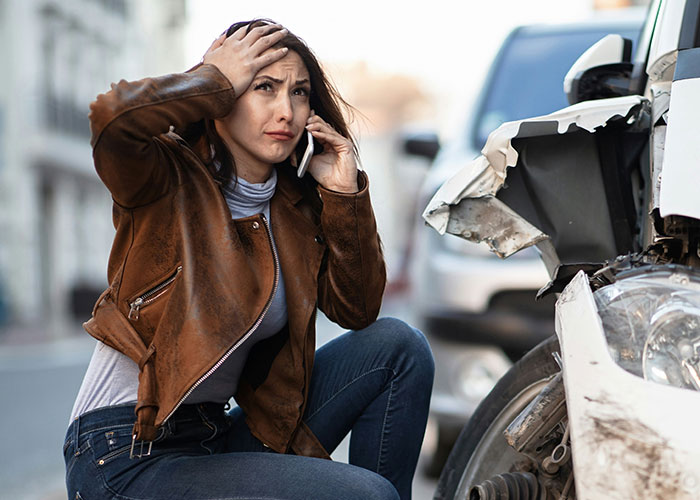 Woman showing frustration after a car accident, capturing a moment of instant karma manifestations on the street.