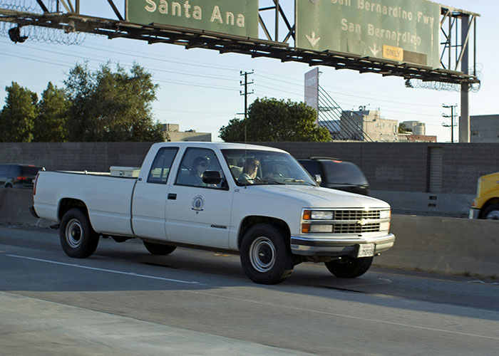 White pickup truck driving on highway with green road signs, illustrating instant karma manifestations in urban traffic.