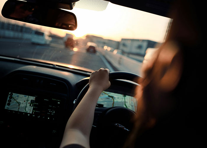 Person driving a car at sunset using GPS navigation, illustrating a moment of instant karma manifestation on the road.