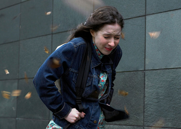 Young woman recoiling in shock as leaves swirl around her, illustrating a vivid moment of instant karma manifestation.