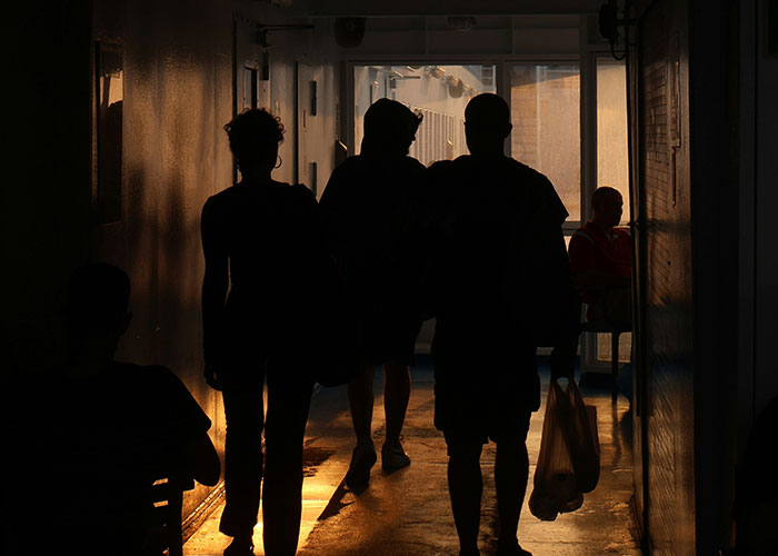 Silhouettes of people walking in a dimly lit hallway capturing instant karma manifestations moments.