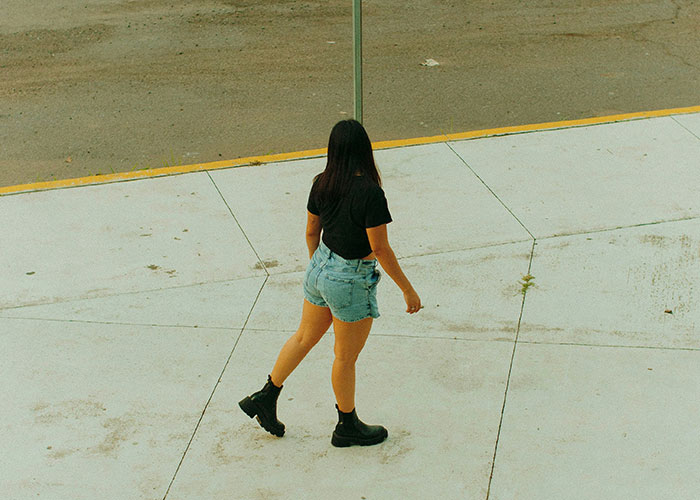 Woman in black shirt and denim shorts walking on sidewalk, illustrating instant karma manifestations concept.