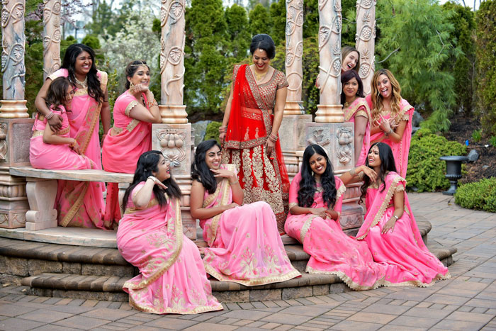 Bride-to-be in red with bridesmaids in pink dresses outdoors, capturing upset emotions about bridesmaid dress payment.