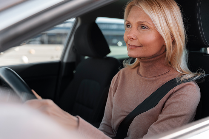 Middle-aged woman driving a car, representing a mom standing her ground on balancing autistic student&rsquo;s needs and injured child.