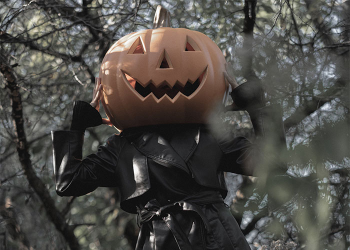 Woman wearing inappropriate Halloween costume with a large pumpkin head, causing tension at a Halloween event.