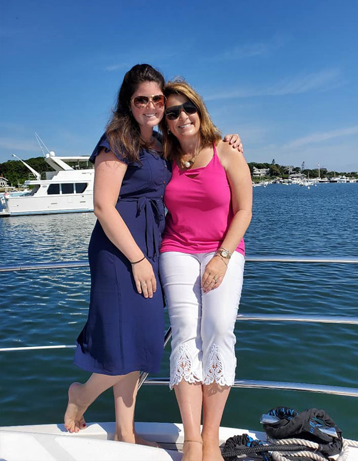 Two women smiling on a boat near the water, representing a woman writing her own obituary with humor.