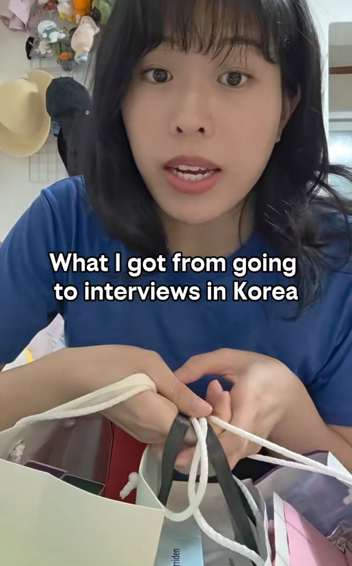 Woman sharing gifts received from job interviews in Korea, showing various gift bags and items with excitement.