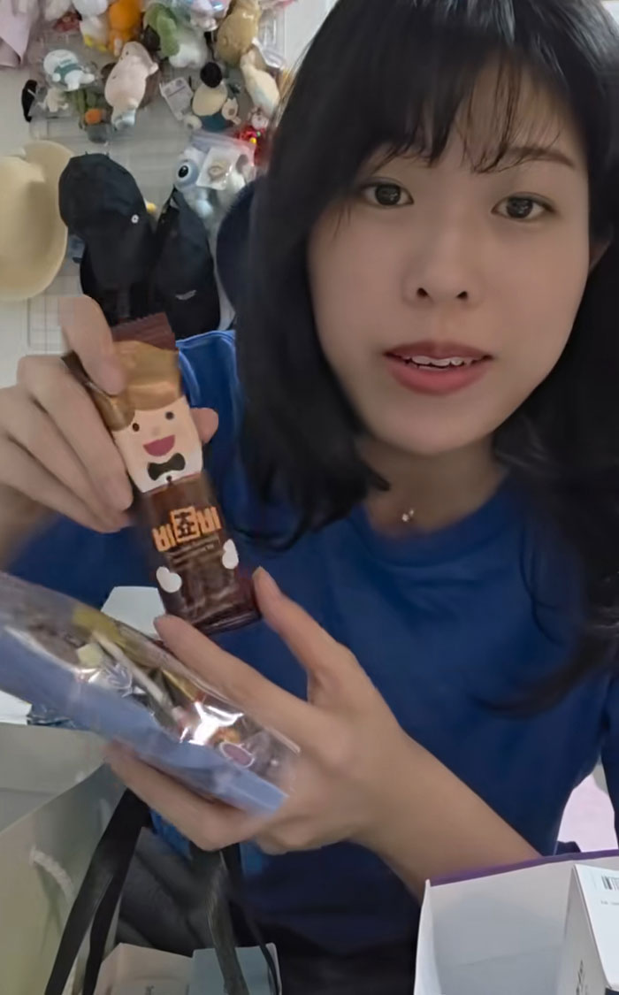 Woman sharing gifts from job interviews in Korea, showing snacks and goodies with excitement and smiling face.