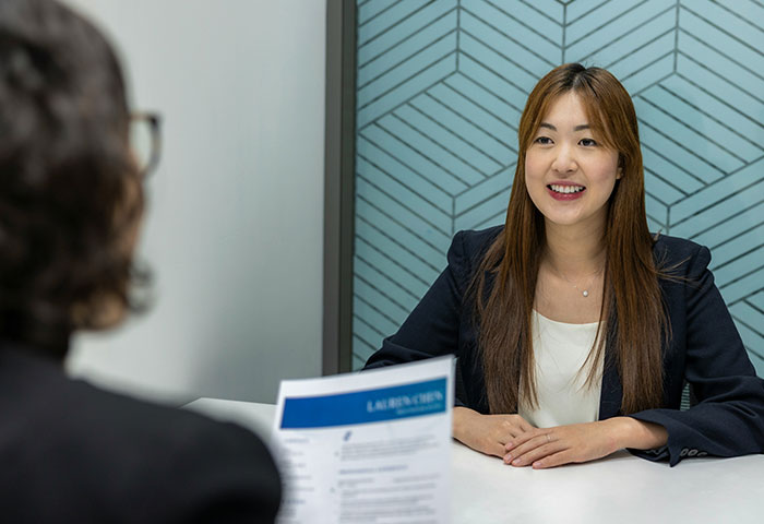 Woman in a job interview in Korea smiling while sharing gifts received during the interview process at a modern office.