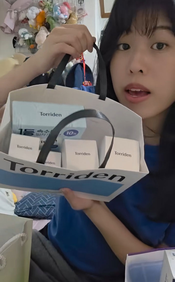 Woman holding a bag of gifts received while interviewing for jobs in Korea, showing excitement and surprise.