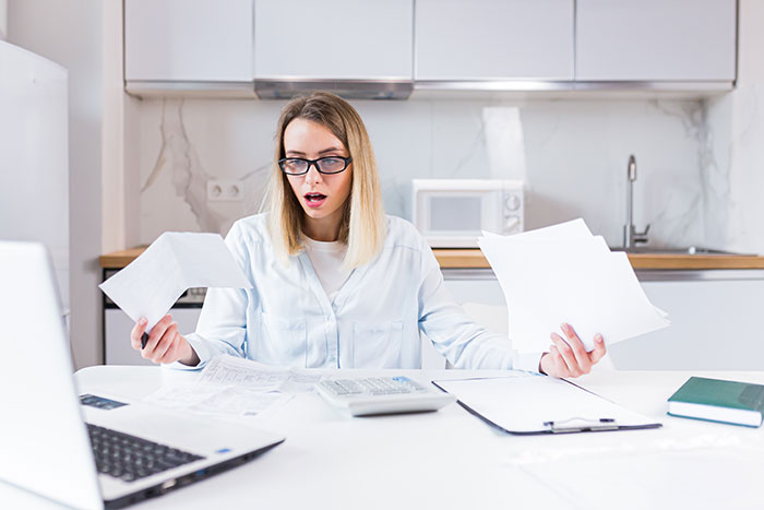 Grieving daughter reviewing financial documents at a kitchen table, determined to drive step-monster to financial ruin.