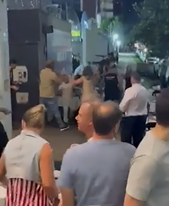 Crowd watching as man intervenes in street altercation involving a woman and a child, highlighting children come first debate.