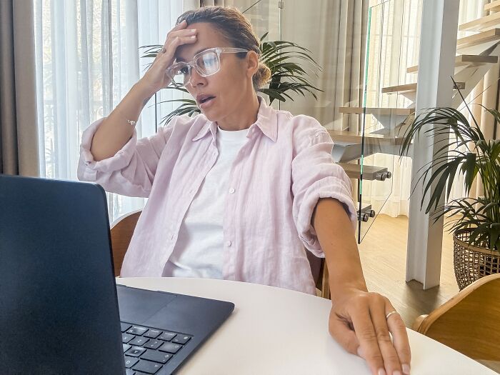 Woman in glasses looking stressed while using a laptop, representing simple car stuff skills for quick learning and results.