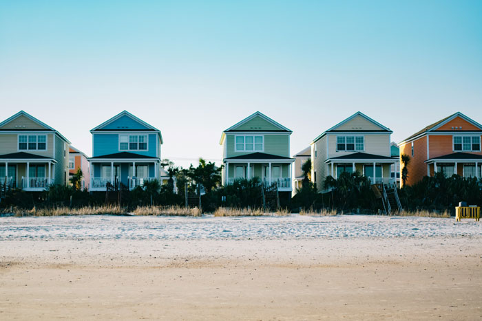 Row of colorful new homes near the beach with fenced yards showing new homeowners enjoying their yard and pool alone