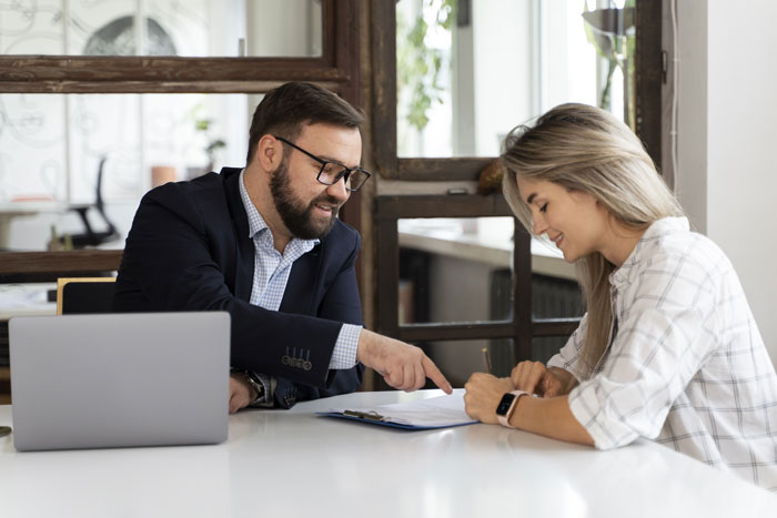 Man in glasses discussing fencing options with woman at table with laptop, focusing on yard and pool privacy for new homeowners