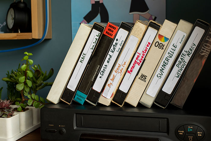 Stack of labeled VHS tapes on a player, evoking babysitter memories and awkward moments from past experiences.