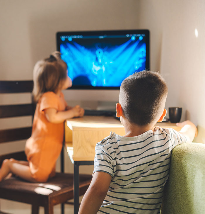 Two kids watching a computer screen inside a room, illustrating babysitters sharing weird and awkward moments.
