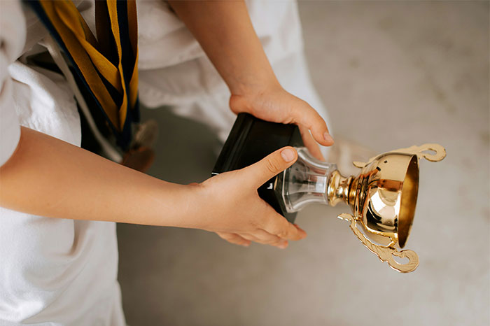 Child in a white shirt holding a trophy upside down, illustrating people who failed spectacularly at work.