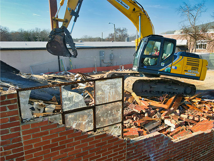 Construction equipment causing a major failure while demolishing a brick wall, showing a spectacular work fail in progress.