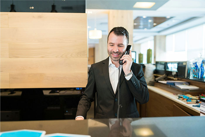 Man in a suit at an office reception desk talking on the phone, illustrating moments people failed spectacularly at work.