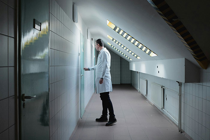Man in white coat standing in a tiled hallway, opening a door, illustrating moments of failing spectacularly at work.