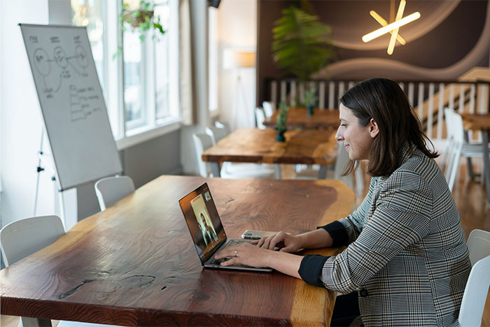 Woman working on laptop in modern office, illustrating moments of people failing spectacularly at work.