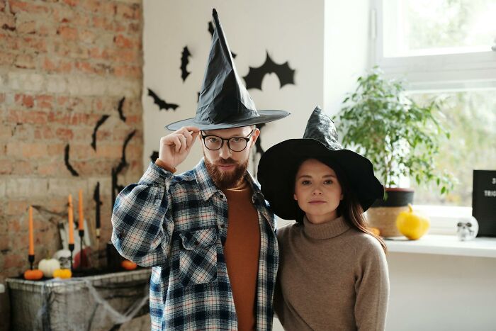 Couple wearing witch hats posing indoors with Halloween decorations, illustrating Halloween experiences that turned into nightmares.