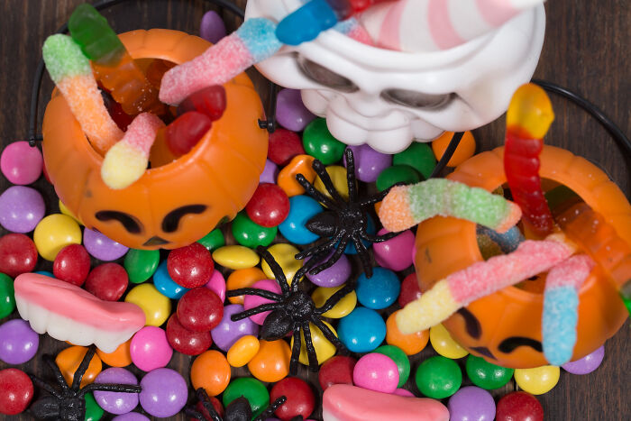 Halloween candy buckets filled with gummy worms, fake spider decorations, and colorful candy for worst Halloween experiences.