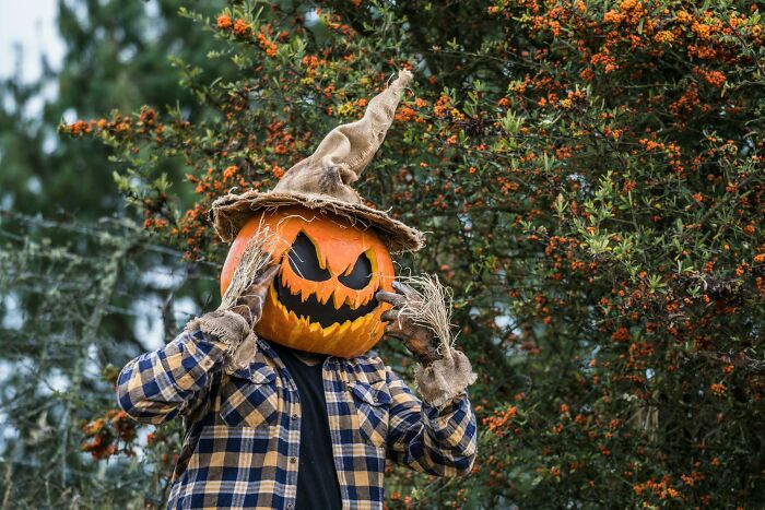 Person wearing a scary pumpkin head and scarecrow costume outdoors, illustrating worst Halloween experiences turning fun into nightmare.
