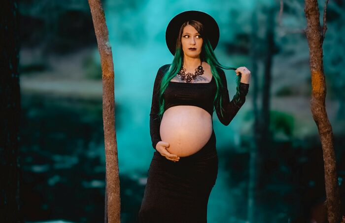 Pregnant woman dressed in a Halloween costume with green hair and a black hat, evoking worst Halloween experiences.