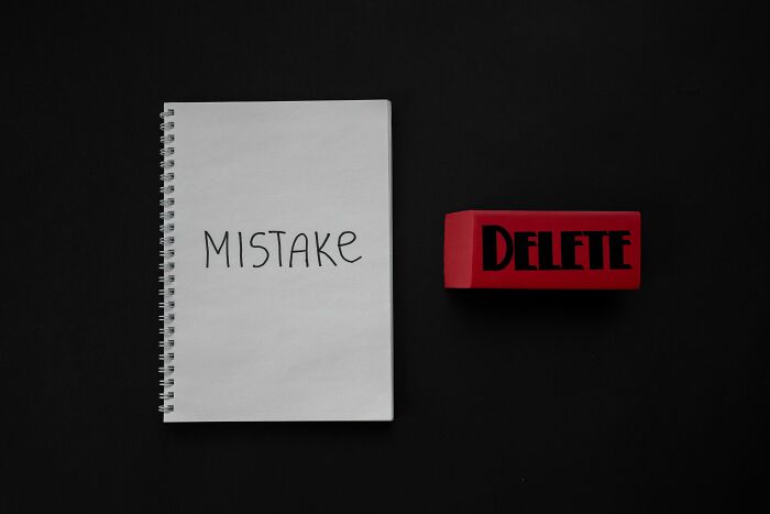 Notebook with the word mistake written on a page next to a red block labeled delete symbolizing mind-bending moral scenarios.